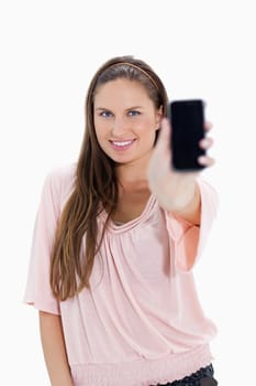 Close-up of a smiling girl showing a smartphone against white background