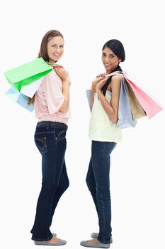 Smiling women carrying a lot of shopping bags against white background