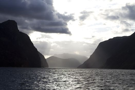 evening view over fjord in norway with cloudy sky and steep coast