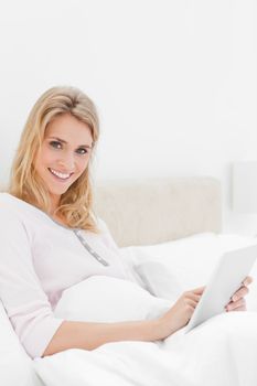 A close up shot of a smiling woman who is using a tablet pc as she is looking up and a bit to the side.