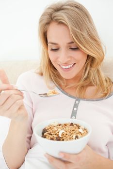 A close up shot of a smiling woman looking at a raised spoon full of cereal.