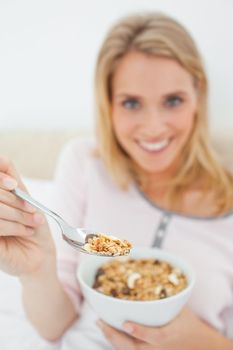 A focused shot of a woman offering a spoon of cereal, the shot focused on the spoon itself.