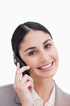 Close up of smiling businesswoman on her cellphone against a white background