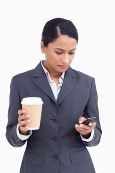 Close up of saleswoman with paper cup writing text message against a white background
