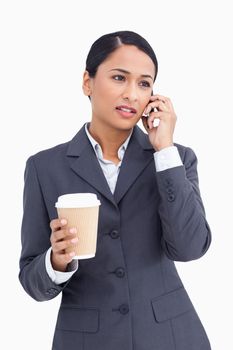 Close up of saleswoman with paper cup talking on cellphone against a white background