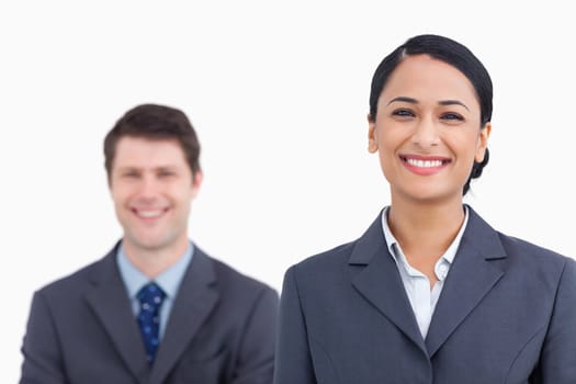 Close up of smiling saleswoman with colleague behind her against a white background