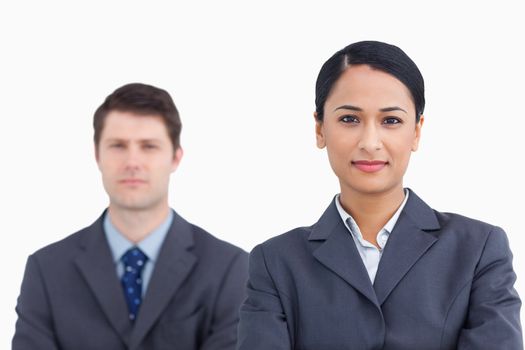 Close up of confident saleswoman with colleague behind her against a white background