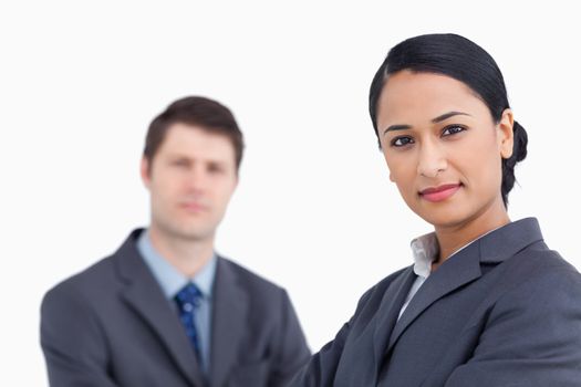 Close up of confident saleswoman with co-worker behind her against a white background