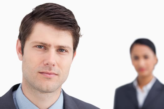 Close up of young salesman with colleague behind him against a white background