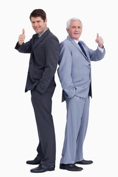 Businessmen standing back to back giving thumbs up against a white background