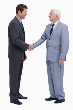 Young and mature businessmen shaking hands against a white background