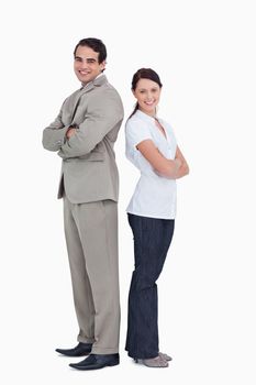 Smiling salesteam with arms folded standing back to back against a white background