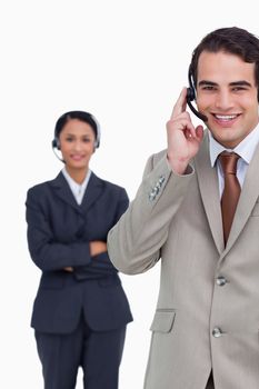 Smiling hotline employee with colleague behind him against a white background
