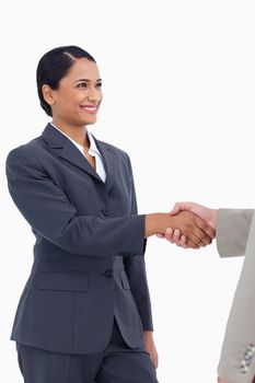 Smiling saleswoman shaking hand against a white background