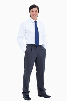 Smiling tradesman with his hands in his pockets against a white background