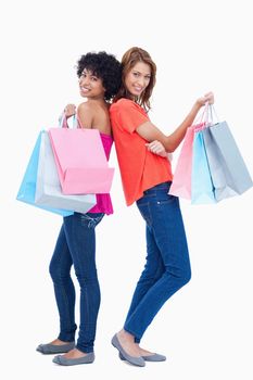 Two smiling teenage girls proudly holding shopping bags