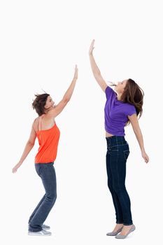 Smiling teenager standing on the tips of her toes while her friend is trying to touch her hand