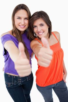 Teenagers smiling a lot while raising their thumbs up in agreement with focus on the teenagers