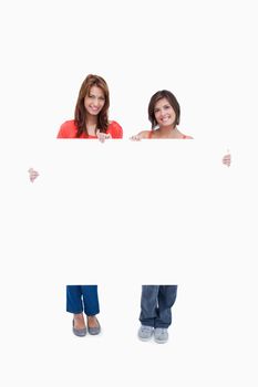 Two smiling teenagers holding a blank poster against a colourless background