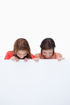 Teenagers smiling and looking at a blank poster while leaning their head forward