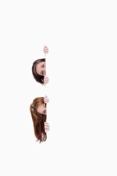 Two teenagers getting their heads out of one side of a blank poster