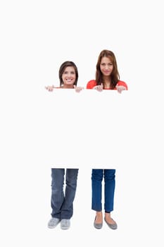 Smiling teenagers proudly holding a blank poster against a white background