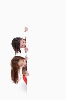 Teenagers showing their heads on the side of a blank poster