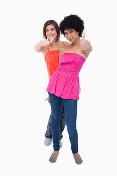 Teenagers showing thumbs up one behind the other against a white background