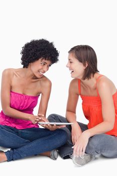 Teenager showing something on her tablet PC to her laughing friend 