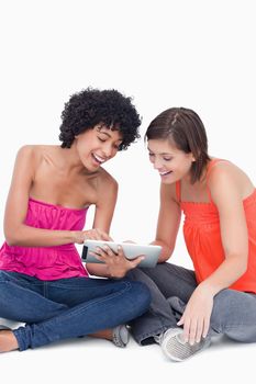 Laughing teenager showing a funny application on her tablet computer to a friend