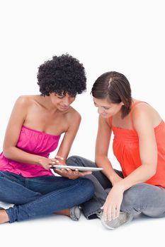 Beautiful teenagers attentively looking at a tablet PC against a white background