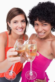 Young females smiling and clinking glasses of white wine