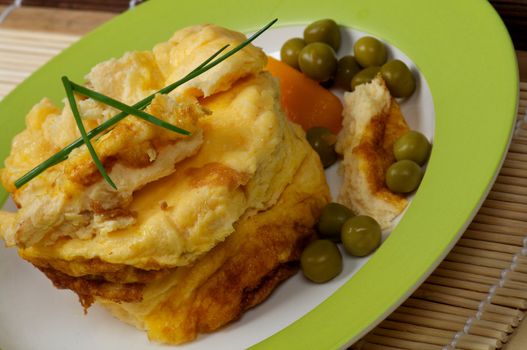 Fluffy Scrambled Omelet with Green Peas and Lettuce closeup on green plate