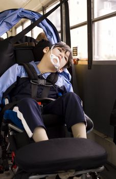 Disabled little boy sitting in wheelchair on school bus