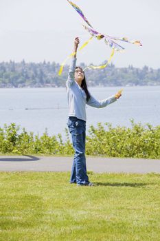 Biracial asian girl flying kite by the lake
