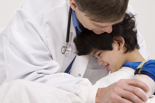 Male doctor in early forties comforting five year old disabled patient 