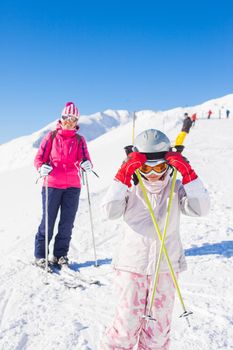 Happy smiling girl in ski goggles and with her mother, Zellertal, Austria