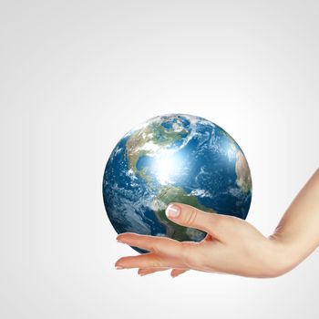 Globe in human hand against blue sky. Environmental protection concept. Elements of this image furnished by NASA