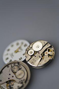 Old metal mechanical clock with gear wheels on a gray background