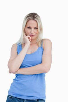 Thoughtful blonde woman placing a finger on her cheek against a white background