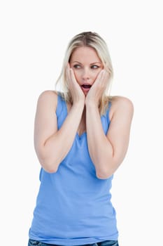 Surprised blonde woman placing her hands on her cheeks against a white background