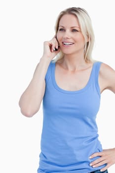 Smiling woman using a mobile phone with a hand on her hip against a white background