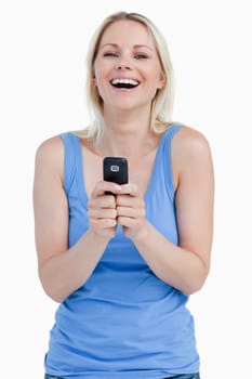 Laughing woman sending a text with her cellphone against a white background