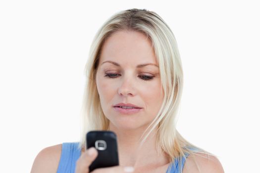 Serious blonde woman holding her cellphone against a white background