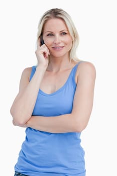 Blonde woman using a cellphone while standing up against a white background