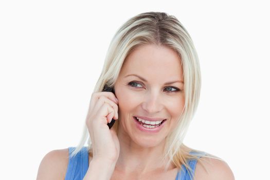 Blonde woman looking on the side while being on the phone and smiling