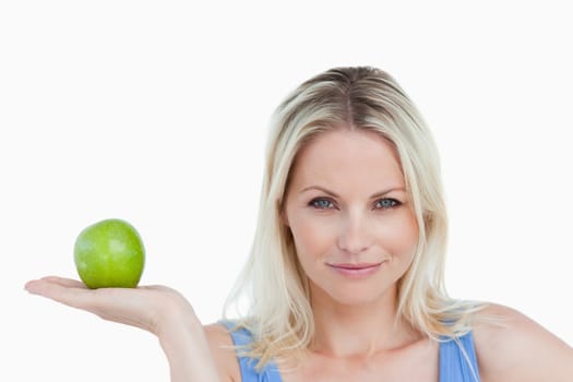 Blonde woman holding an apple in her hand palm against a white background