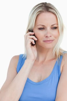 Relaxed blonde woman talking on phone against a white background