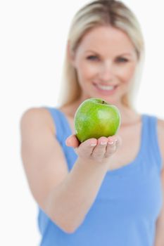 Delicious green apple held by a smiling blonde woman against a white background