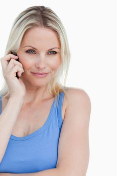 Relaxed blonde woman calling with her cellphone against a white background